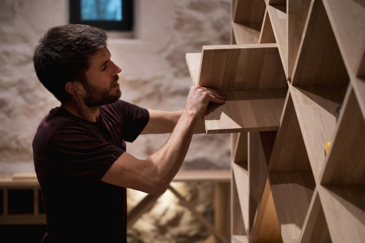 Artisan de Cave d'Origine installant un casier en bois dans une cave