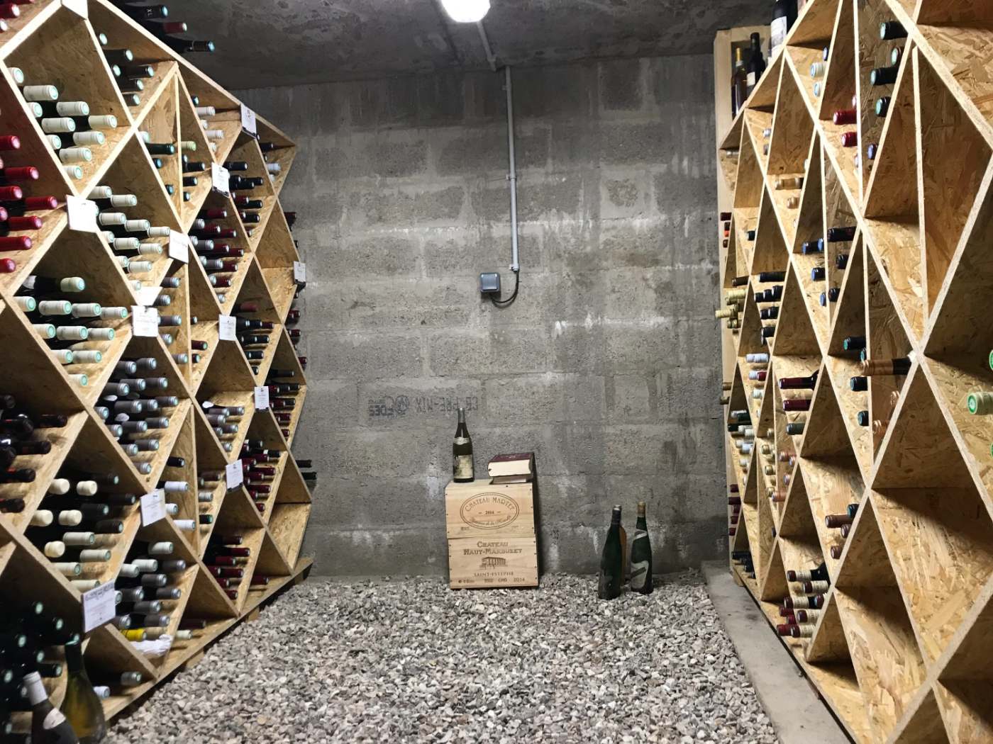 Cave à vin sur mesure avec casiers en bois en losange sur deux murs, réalisée par Cave d'Origine